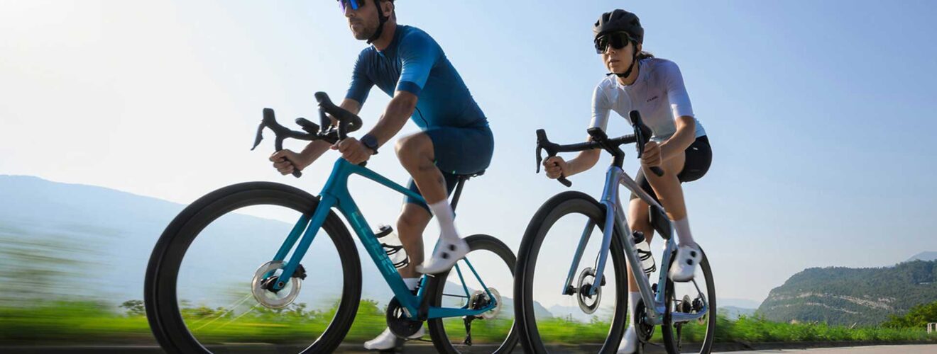 Deux cyclistes sur route (un homme et une femme) roulent sur un vélo Cube 2026 en action.