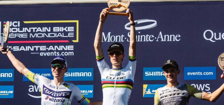 Finn Treudler célèbre la finale de la saison du Cube Factory Racing 2025 à Mont-Sainte-Anne, tenant le trophée dans ses mains, entouré des deuxième et troisième coureurs sur le podium.