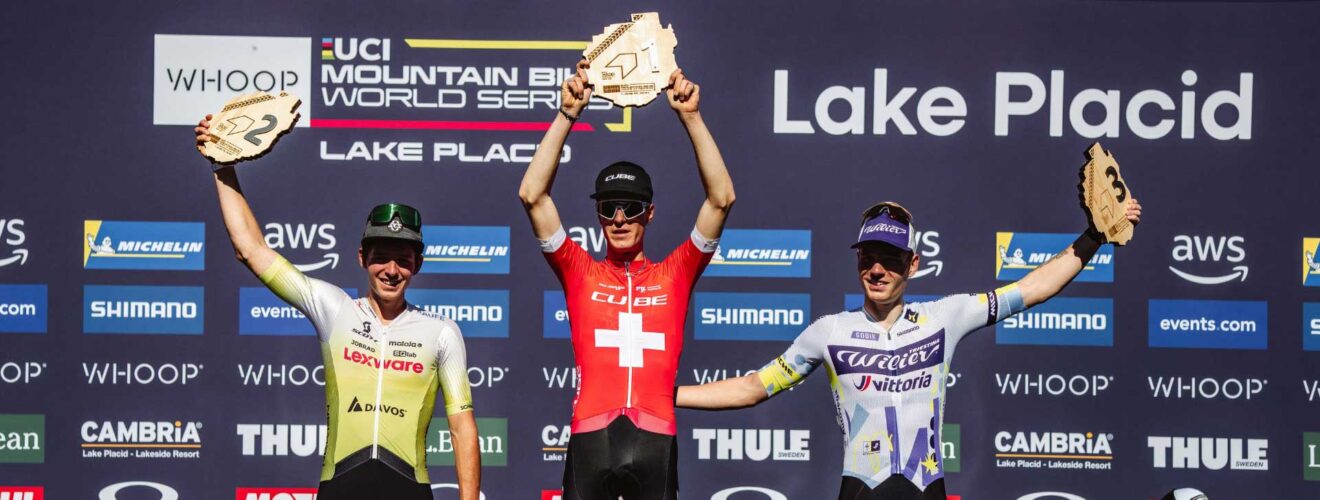Finn Treudler célèbre sur le podium, levant fièrement le trophée de son triomphe U23 à Lake Placid.