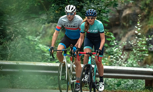 Un homme et une femme font du vélo de cyclocross sur la route.