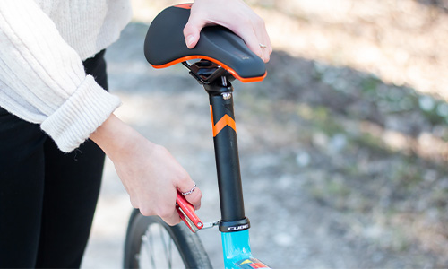 On voit une personne qui serre la vis de la tige de selle.