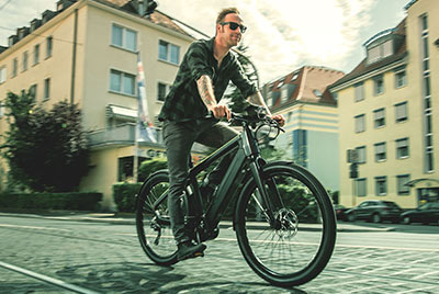 On voit un homme sur un vélo Winora qui roule dans le centre-ville.