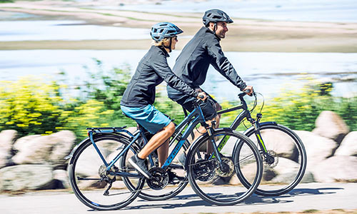 Un homme et une femme roulent à vélo le long de la mer.