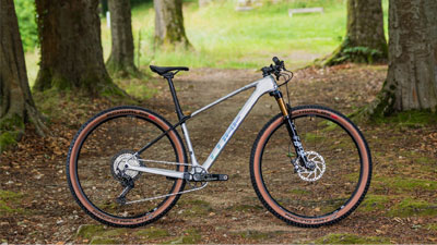 On voit un VTT Cube argenté sur un chemin forestier.
