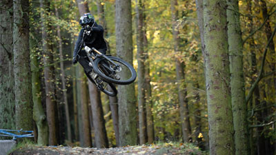 Cycliste avec casque intégral sautant en l'air avec un vélo tout terrain Cube Stereo ONE77.