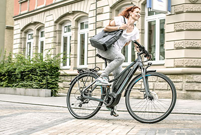 Une femme traverse le centre-ville avec un sac à main sous le bras, sur un vélo Winora.