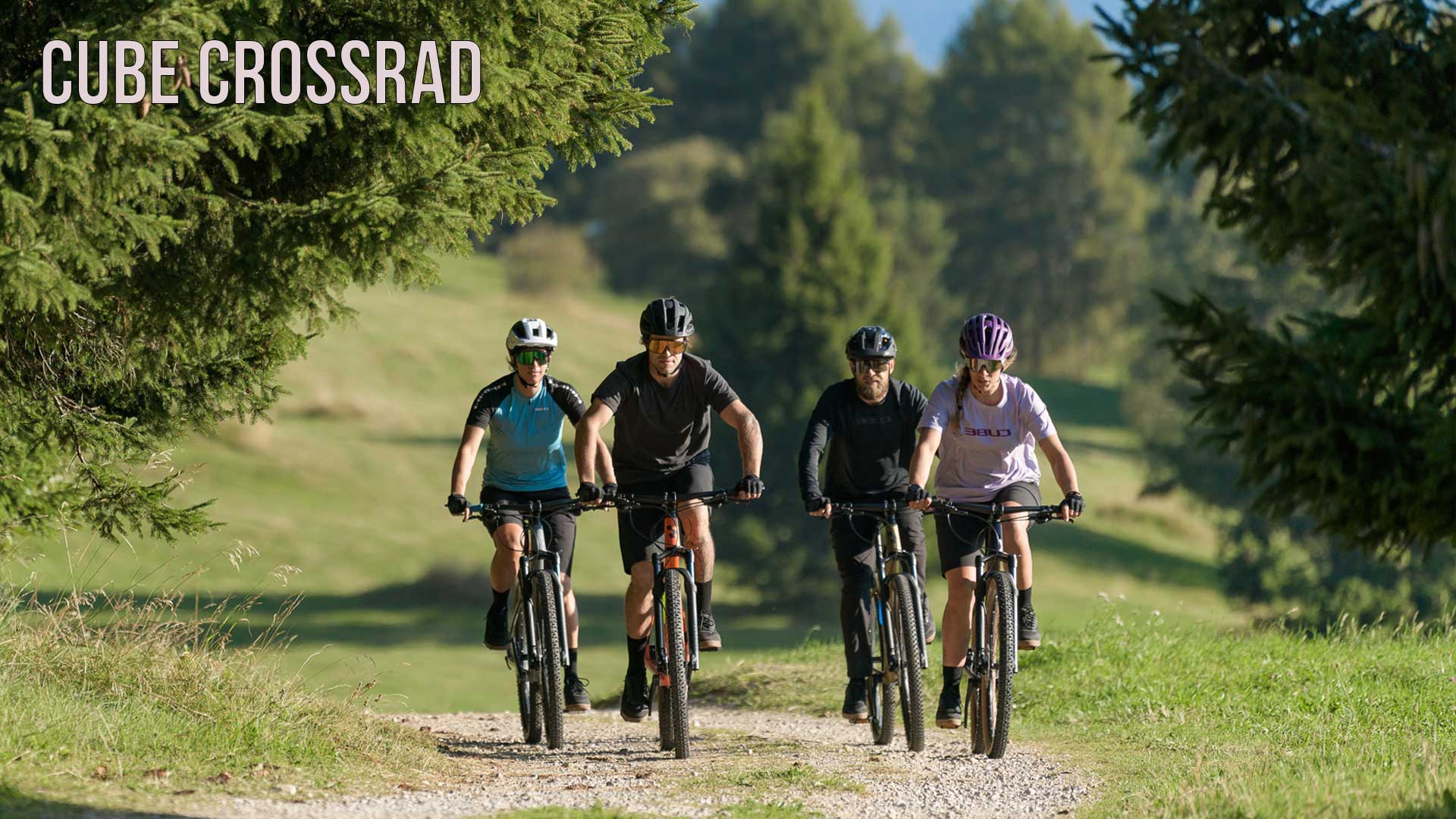 On voit un groupe de cyclistes roulant sur un chemin forestier. L'image est accompagnée du titre Cube Crossrad .