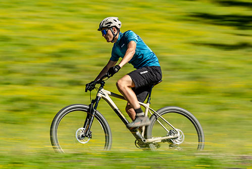 Cycliste avec un t-shirt bleu et un casque sur un VTT semi rigide Cube Reaction.