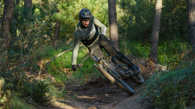 Un cycliste traverse la forêt en diagonale sur un VTT Cube Stereo.