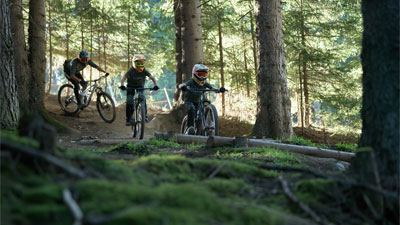 Deux adolescents et un cycliste traversent la forêt sur des vélos tout terrain Cube Stereo.